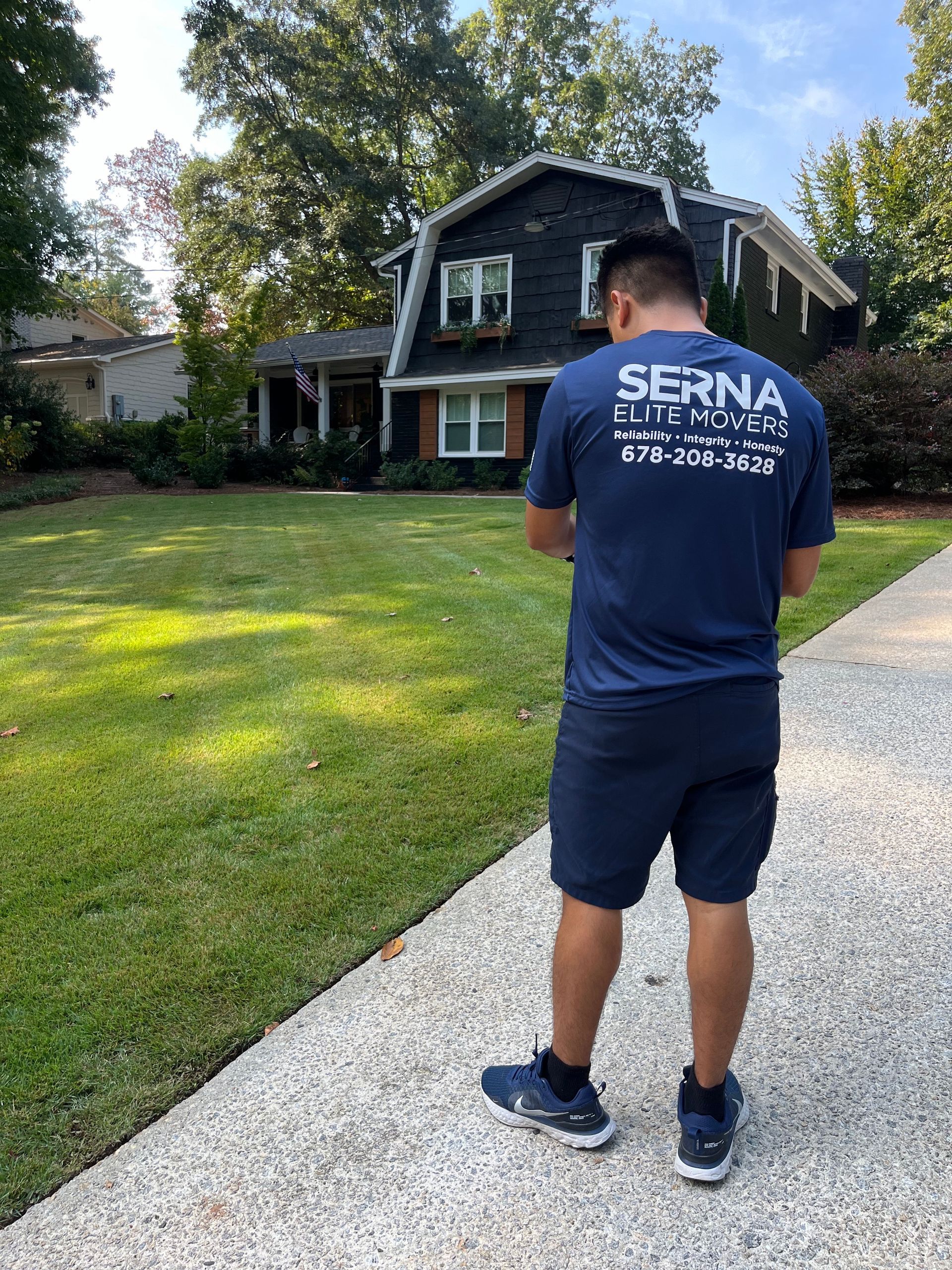 A man is standing on a sidewalk in front of a house.