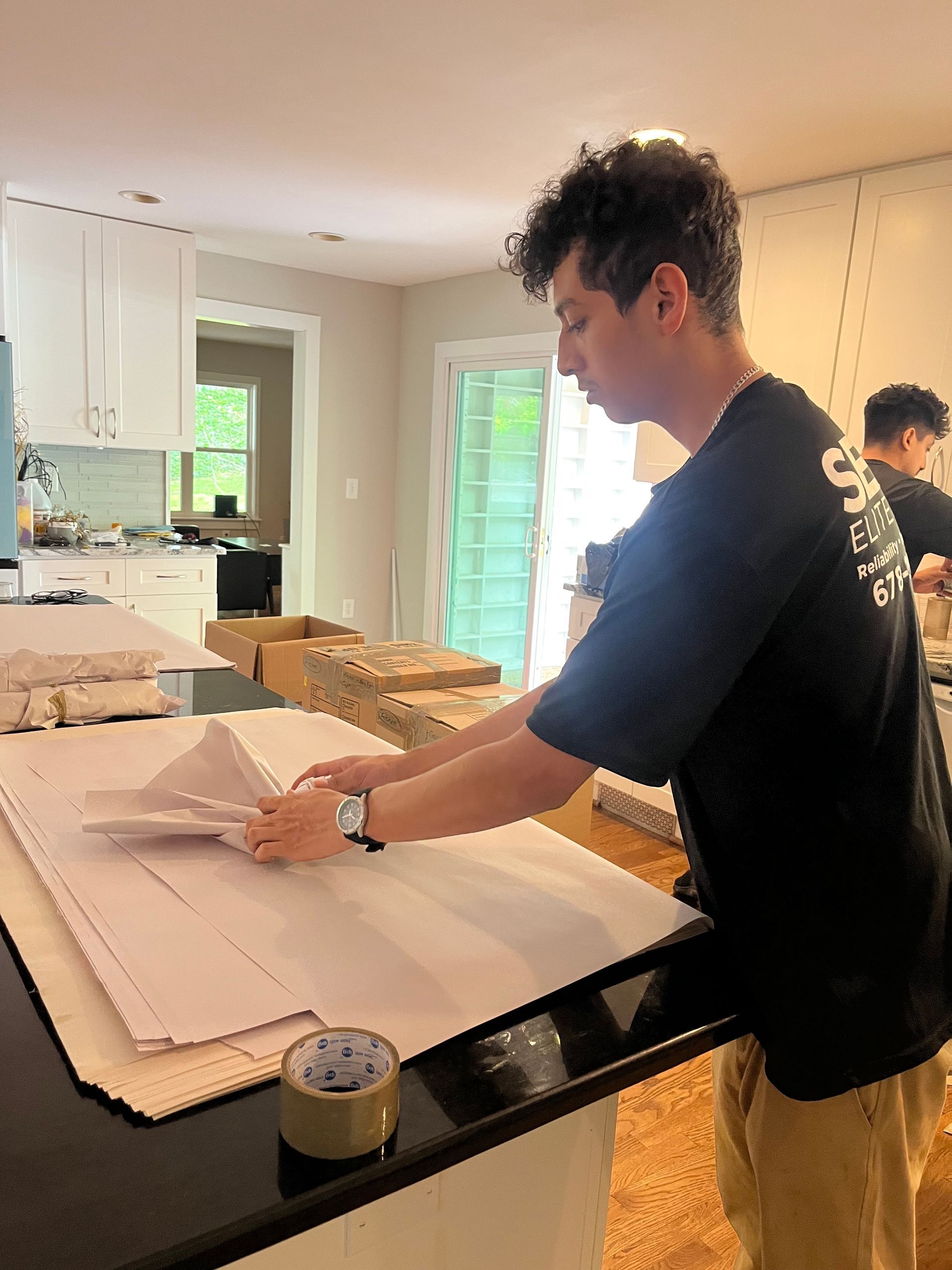 A man is standing in a kitchen looking at a piece of paper.