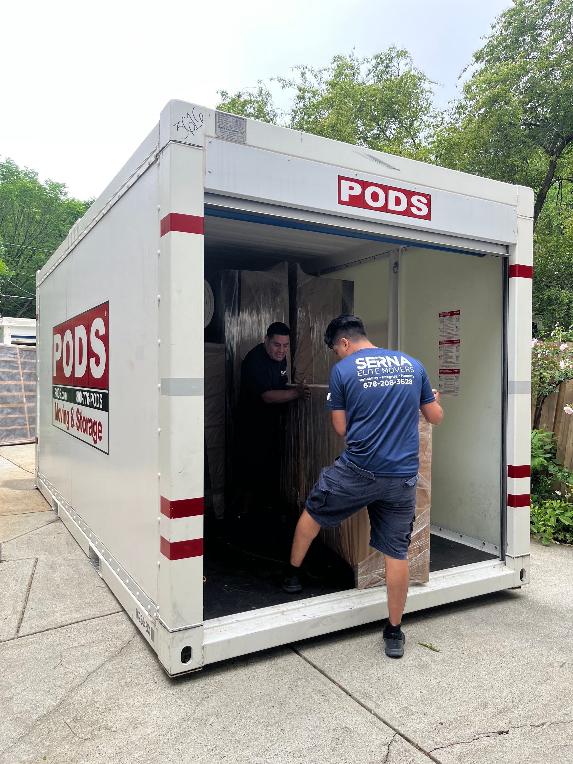 Two men are loading boxes into a pods storage container.