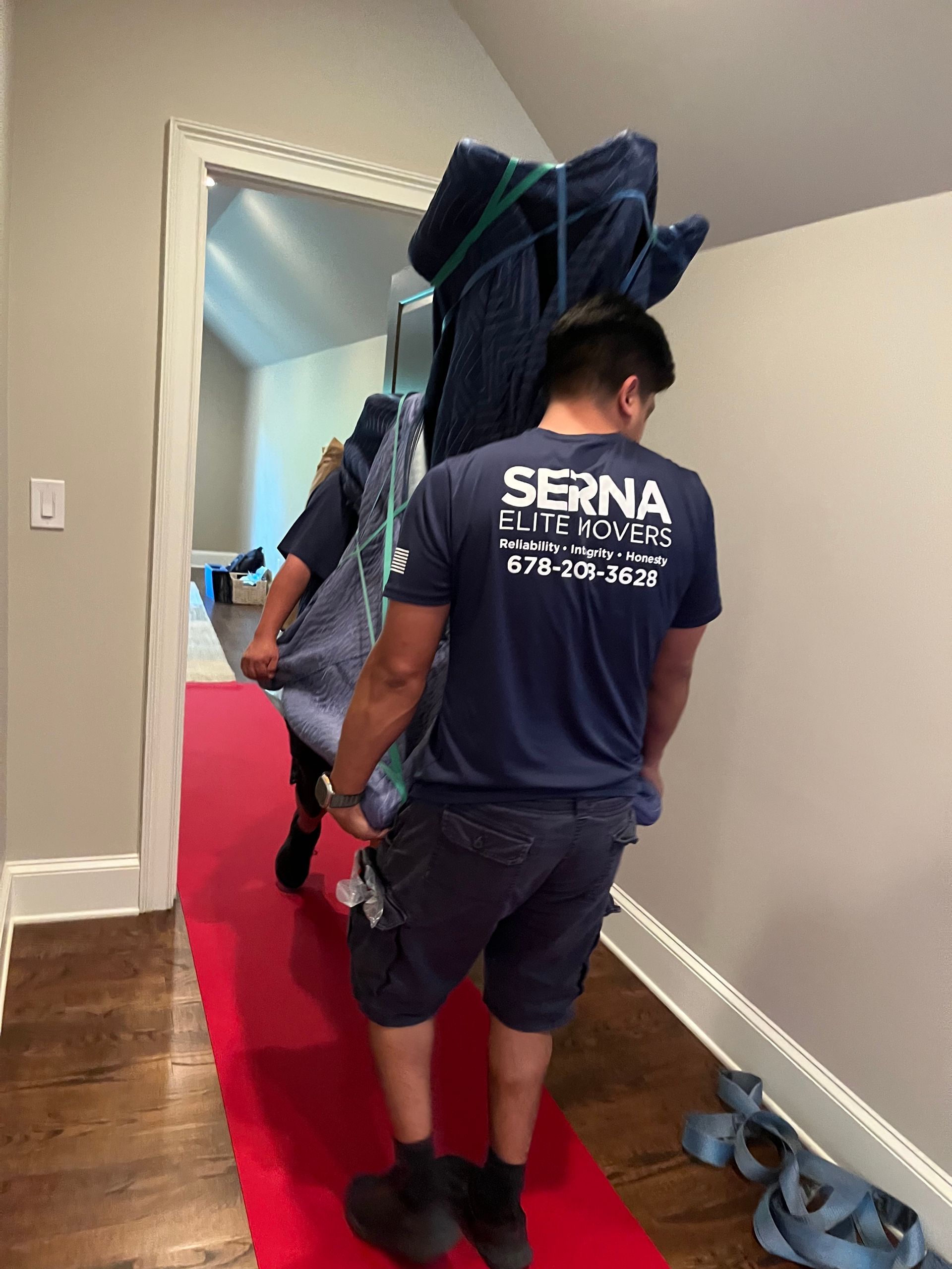 A man is carrying a large piece of furniture on his back.