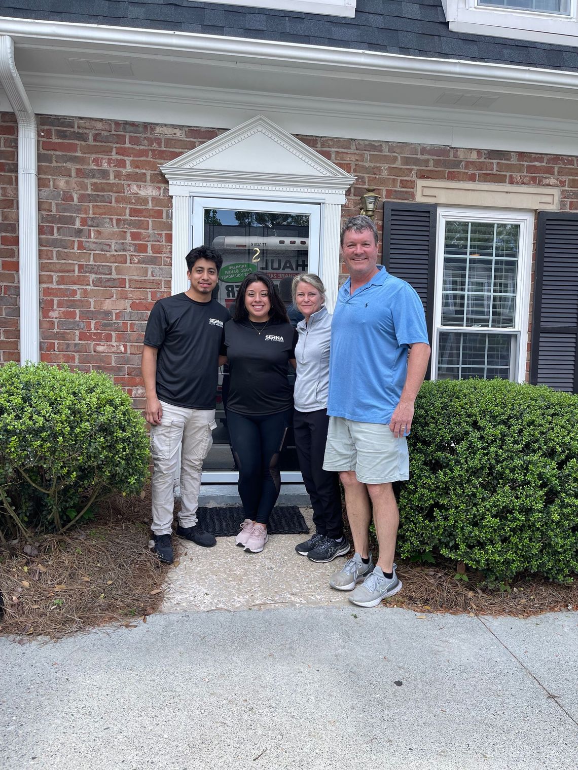 A group of people are standing in front of a brick house.