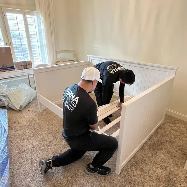 Two men are working on a bed frame in a bedroom.