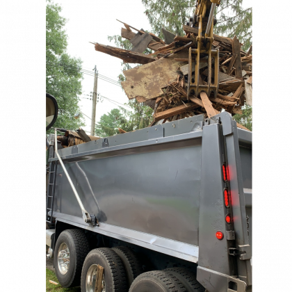 A dump truck is filled with a pile of wood.