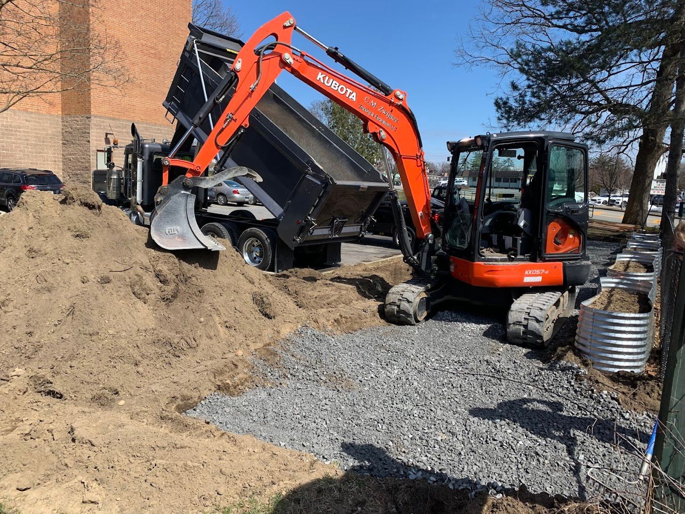A dump truck is being loaded with wood by an excavator.