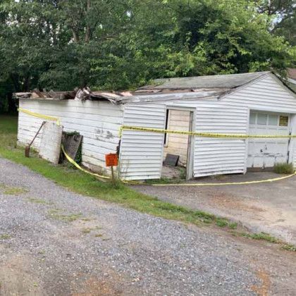 A white shed with a yellow tape surrounding it.