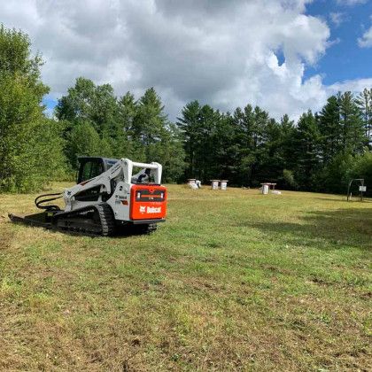 A bobcat is sitting in the middle of a grassy field.