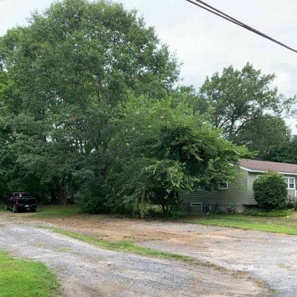 A house with a lot of trees in front of it and a truck parked in front of it.