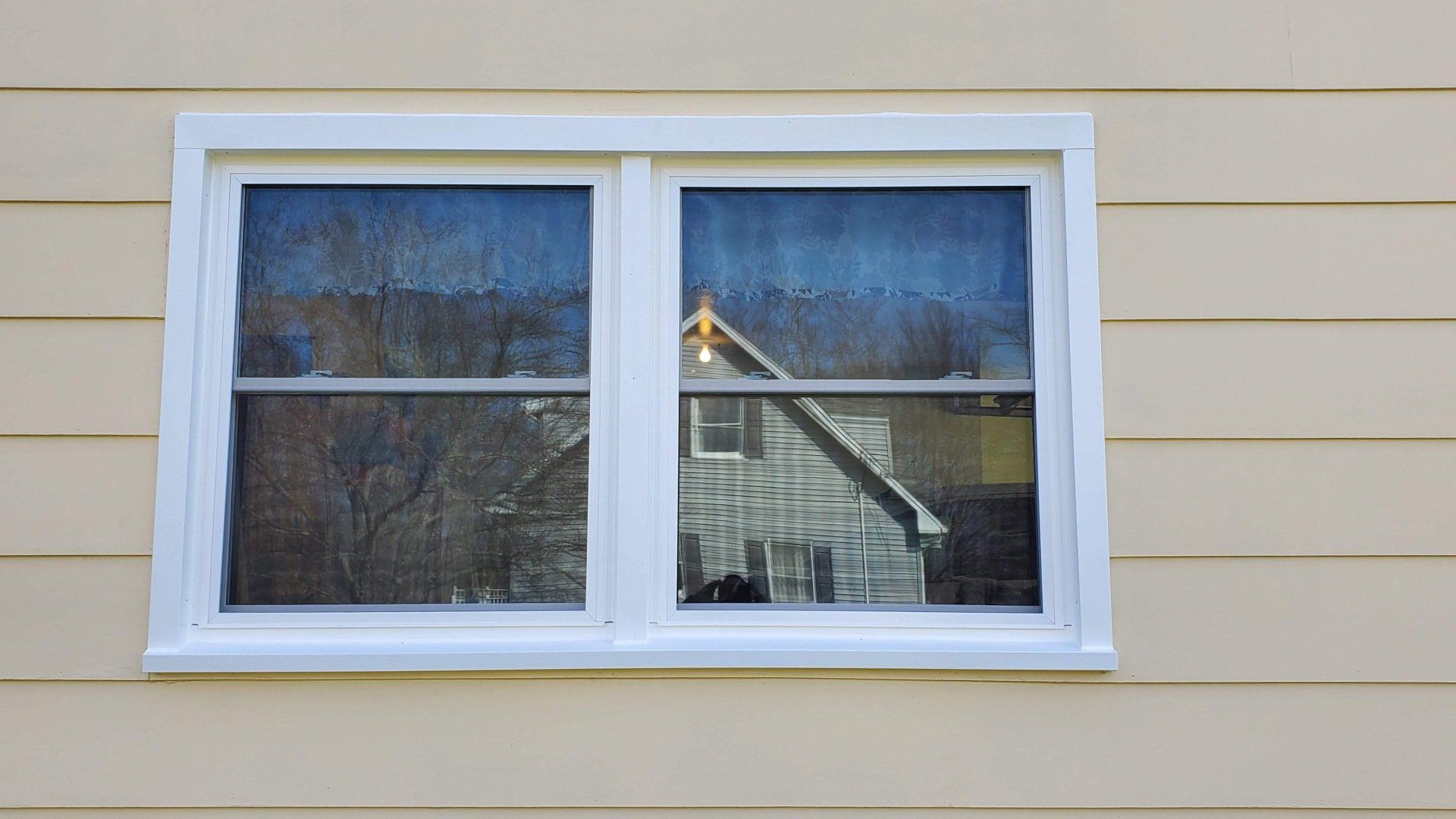 A white window is on the side of a house.