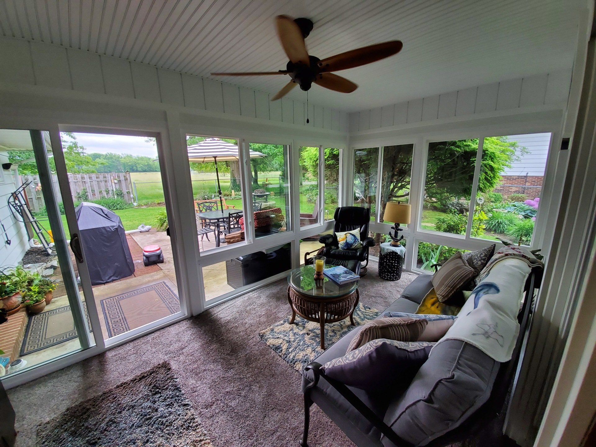 A living room with a lot of windows and a ceiling fan.