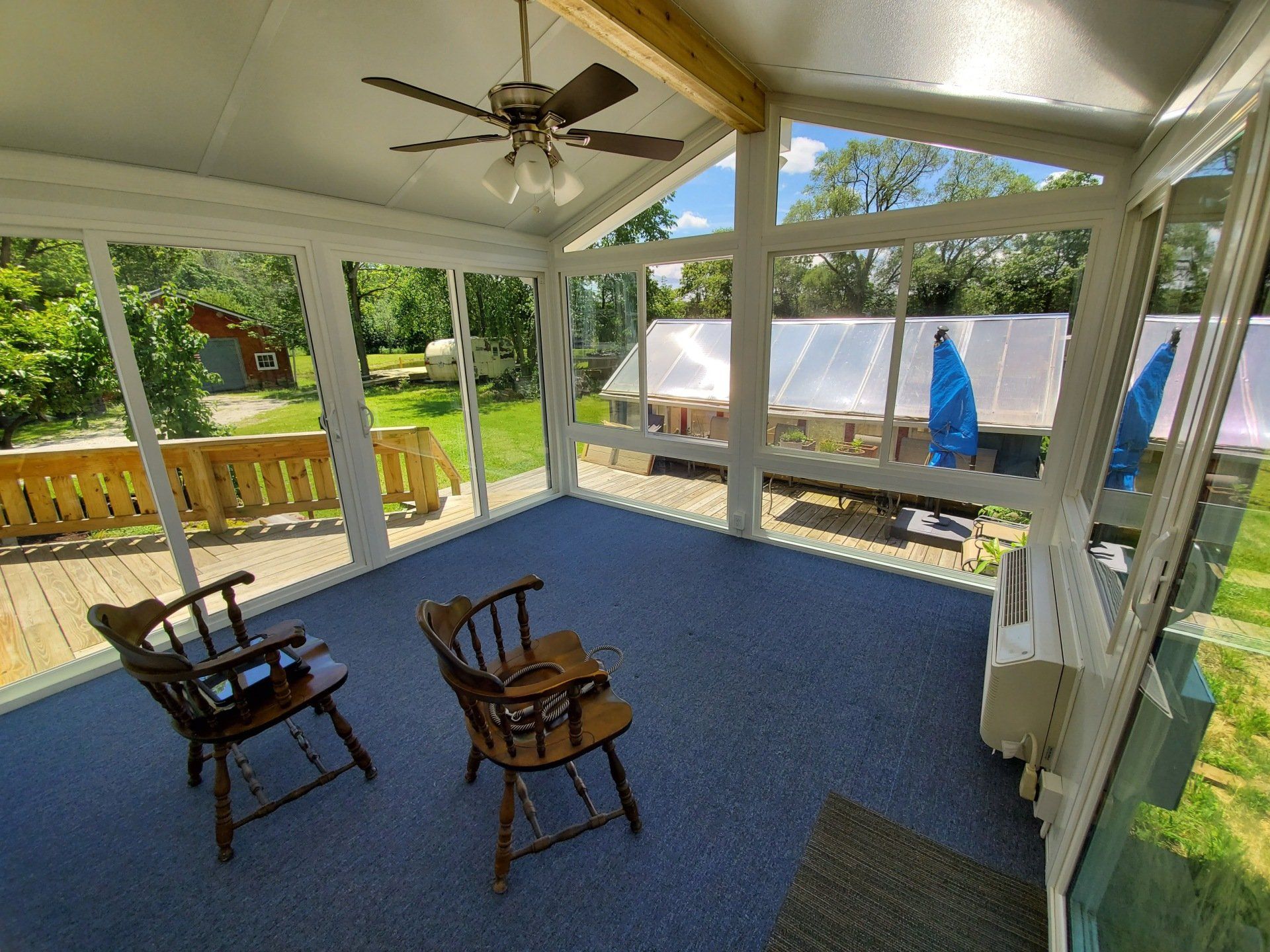 A screened in porch with two rocking chairs and a ceiling fan.