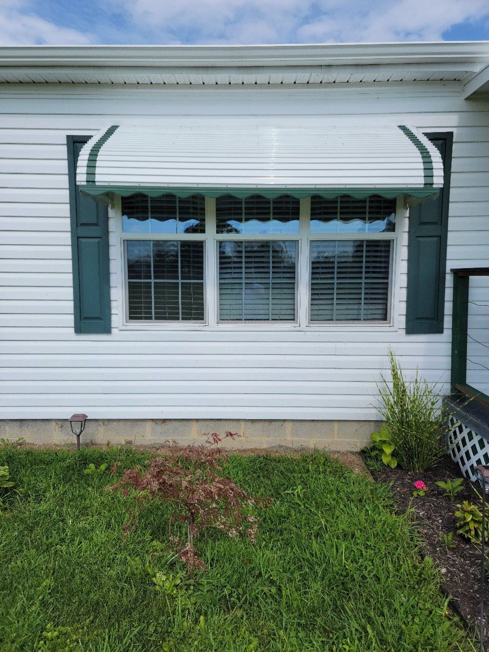 A white mobile home with a green awning over the window.