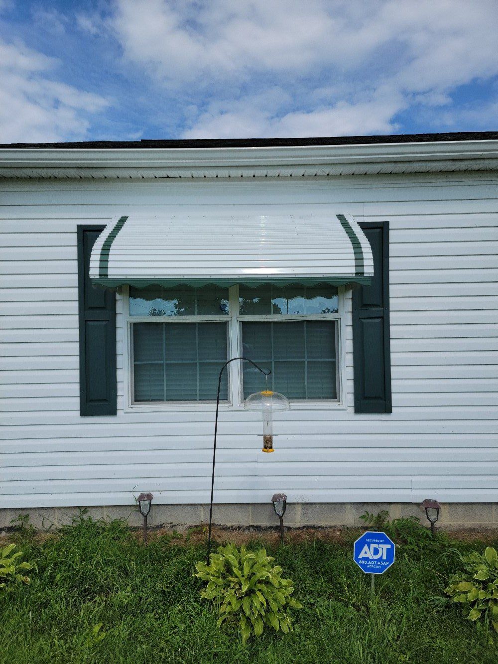A white house with a green awning over a window.