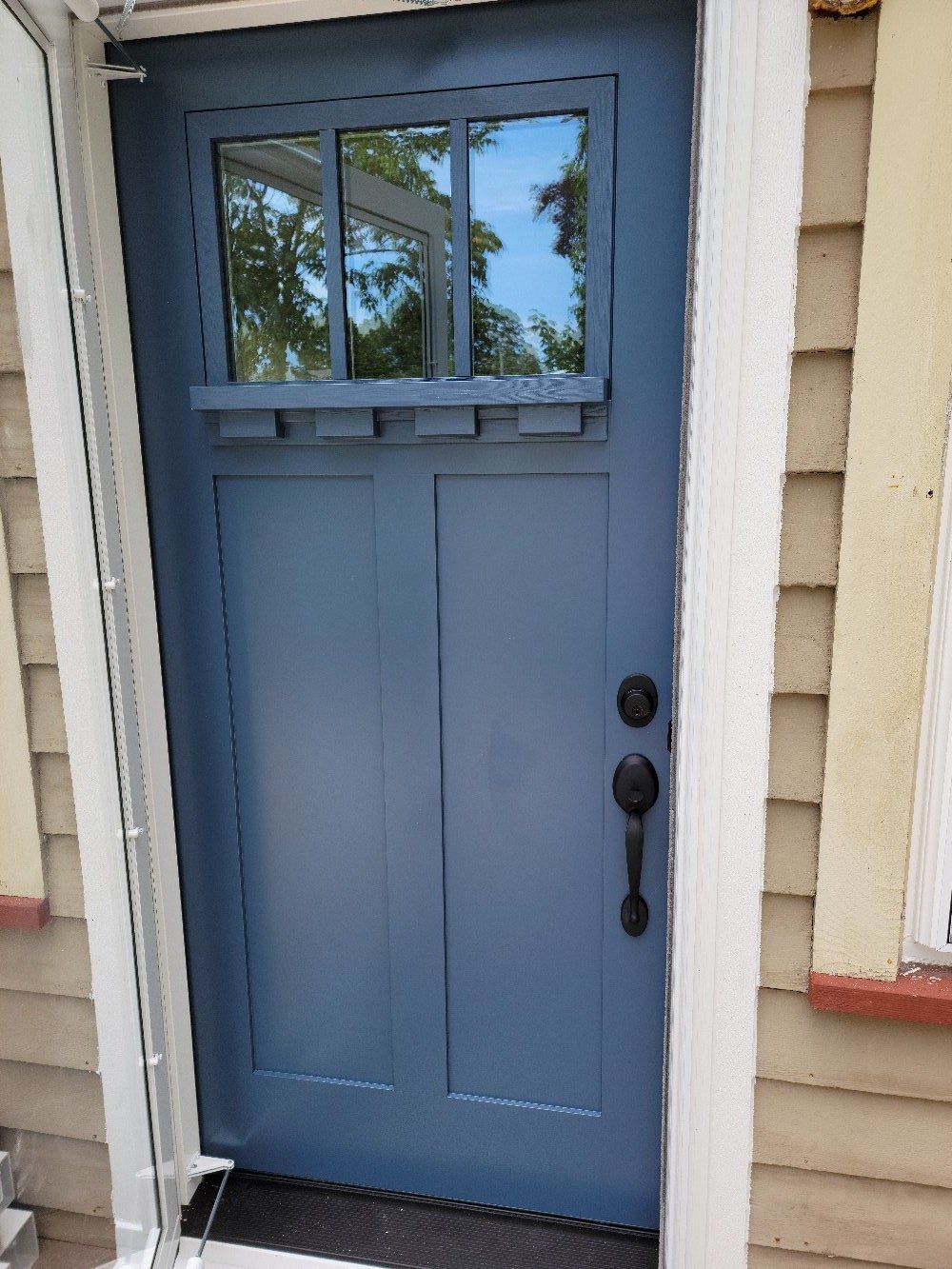 A blue door with a window on the side of a house.