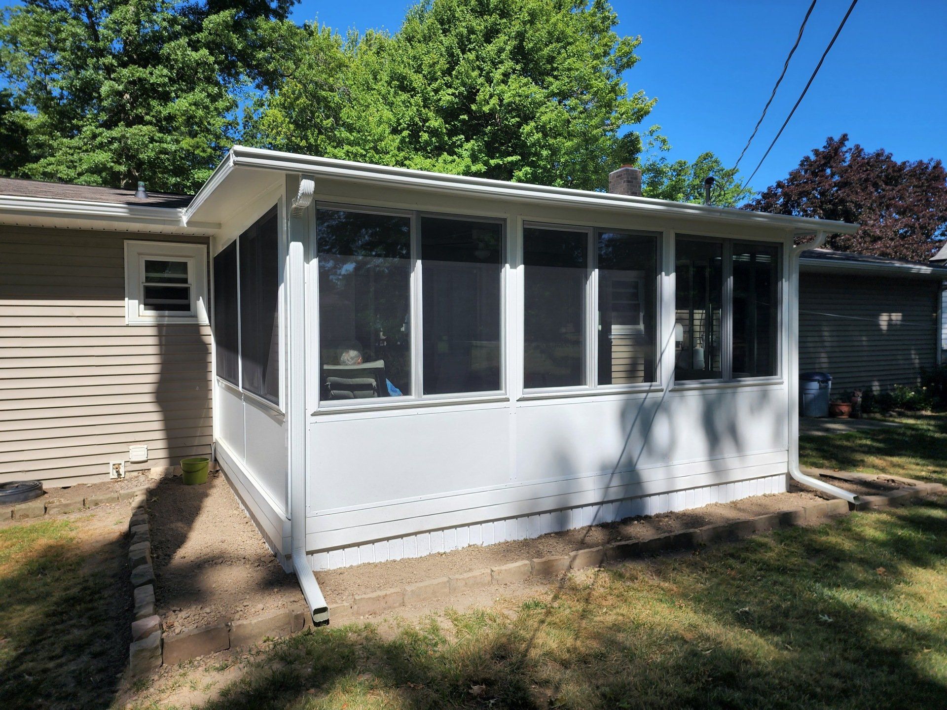 A screened in porch in the backyard of a house