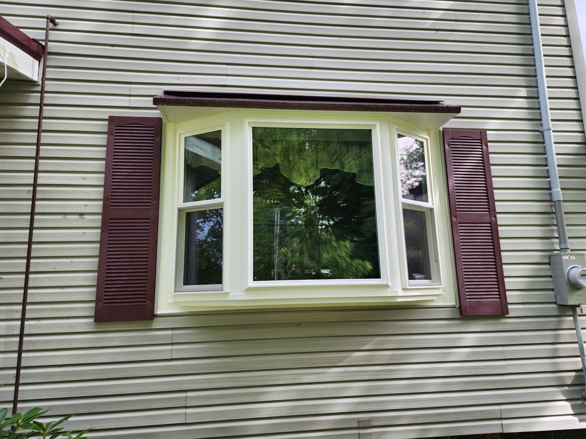 A window with shutters on the side of a house.