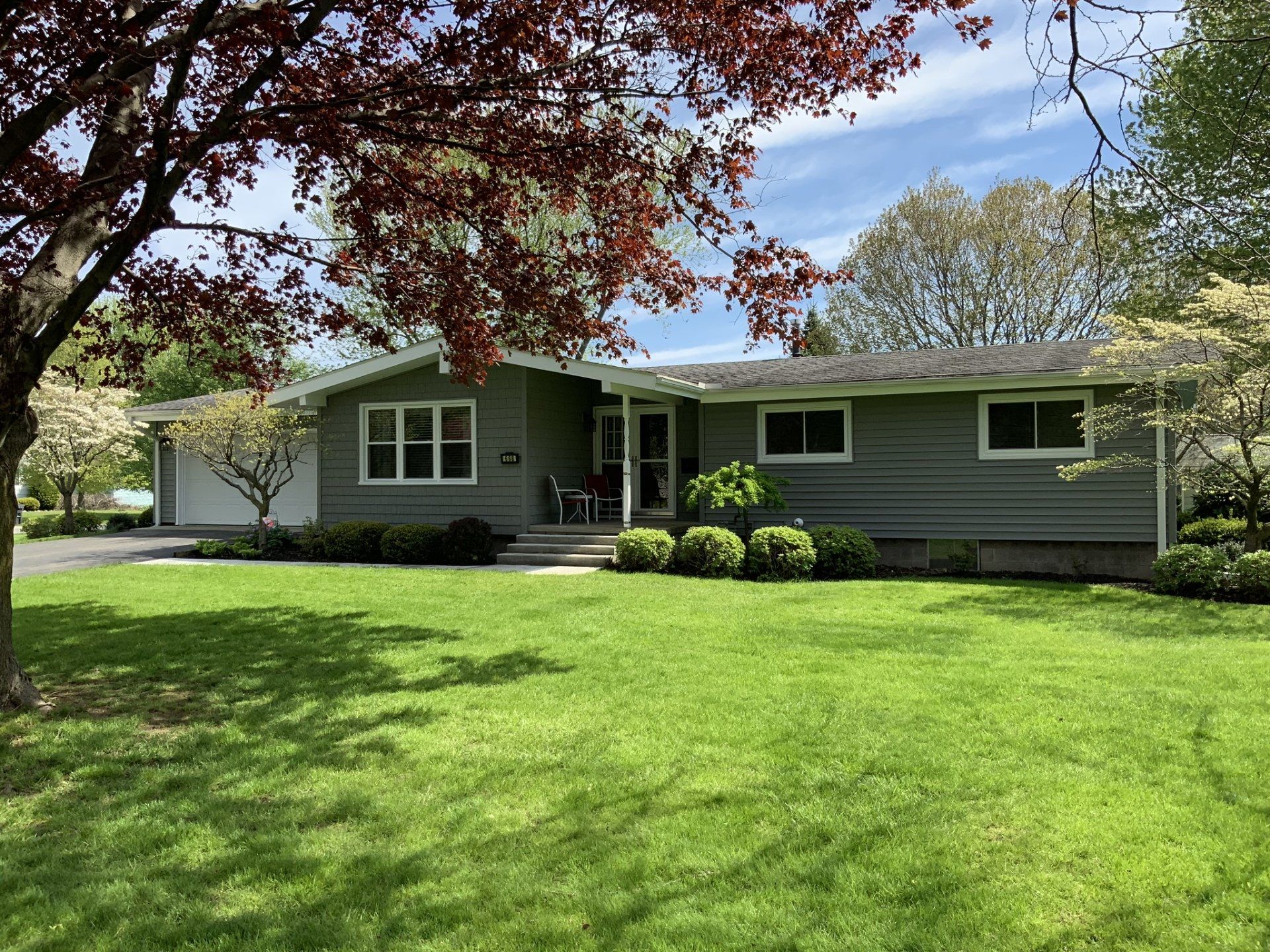 A house with a large lawn and a tree in front of it