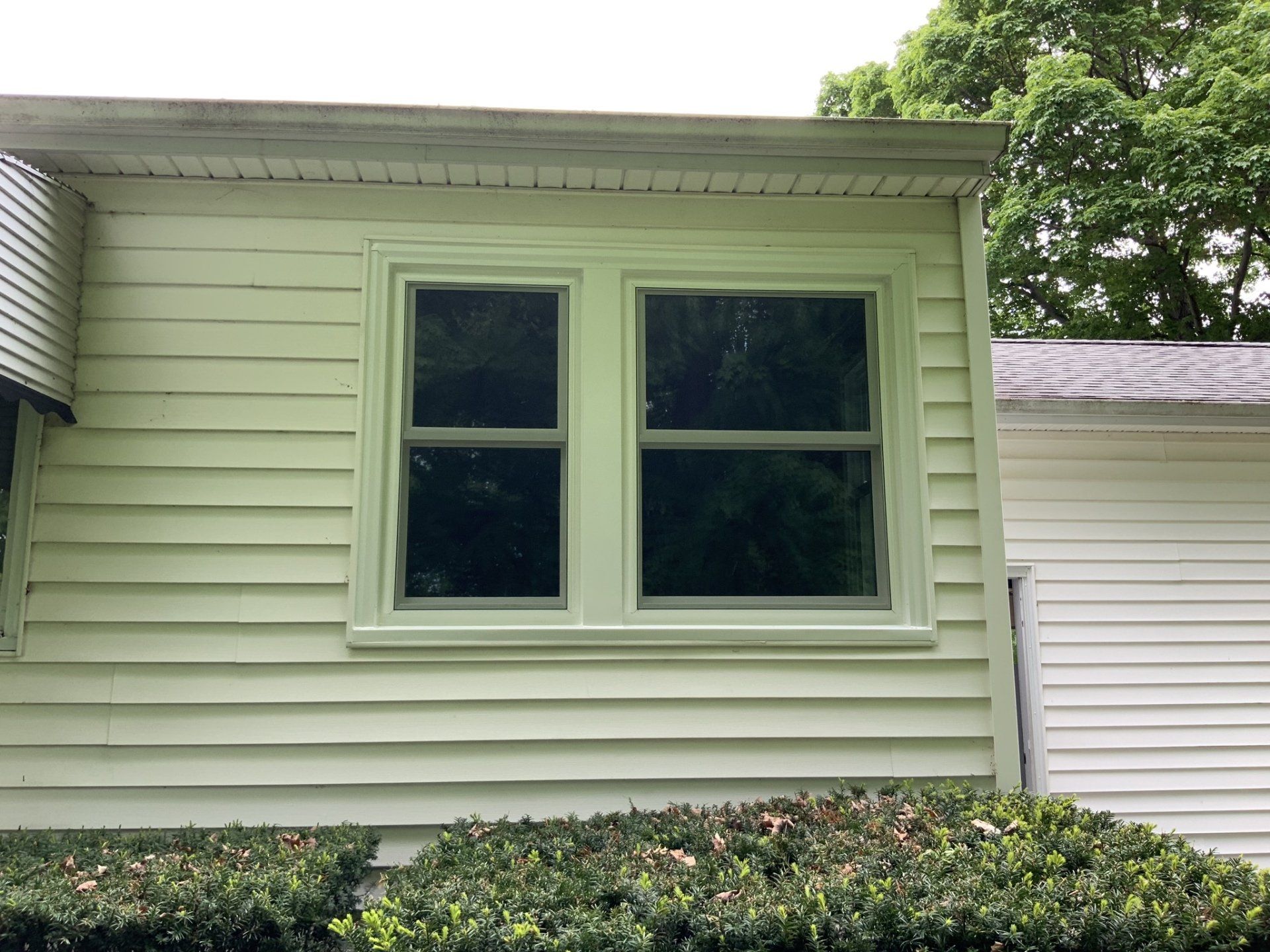 A white house with a green window on the side of it.