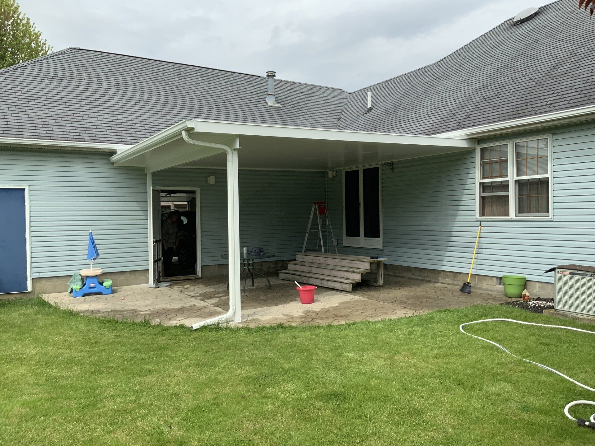 A blue house with a covered patio in the backyard.