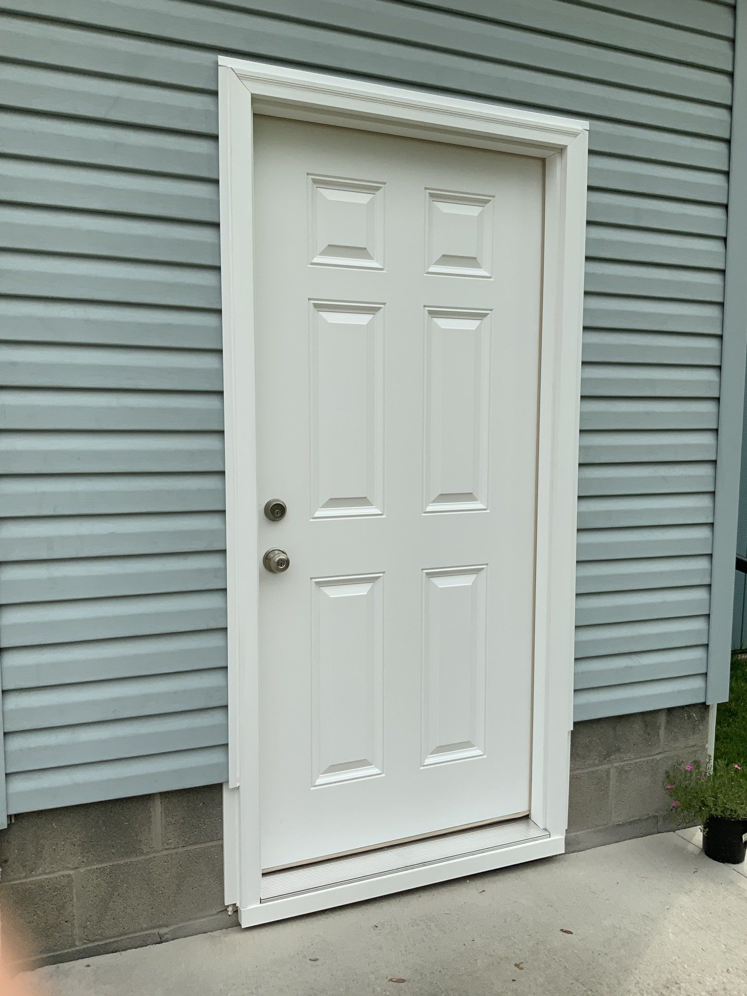 A white door is sitting on the side of a house.