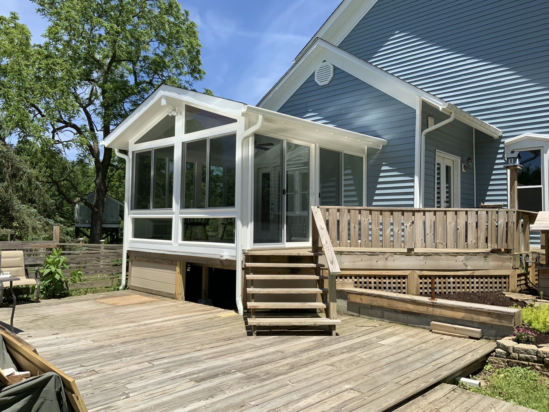 A house with a screened in porch and a wooden deck.