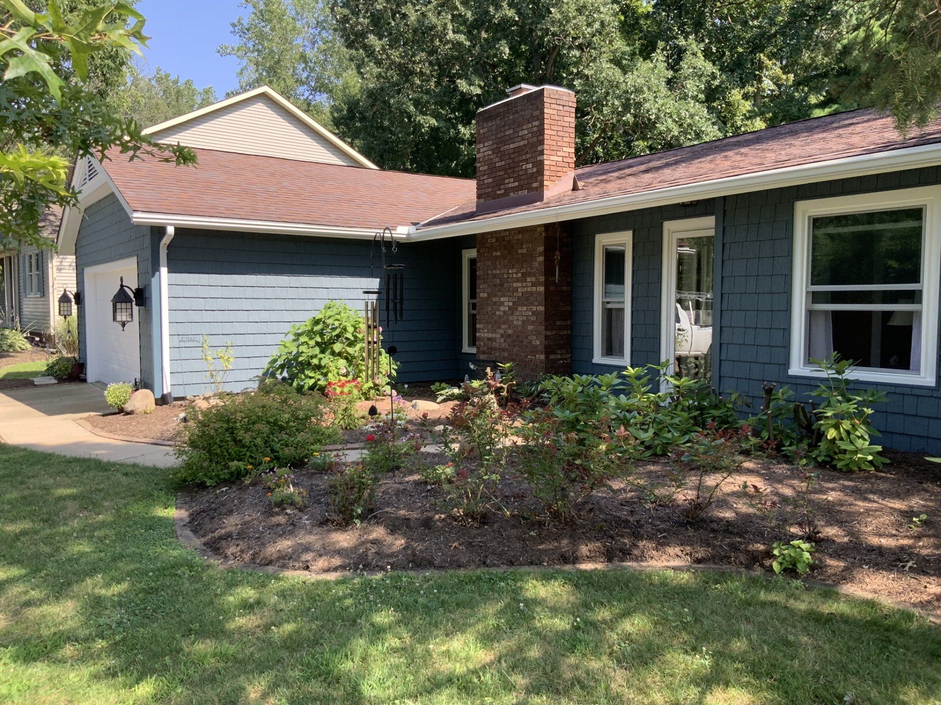 A blue house with a brown roof and a brick chimney
