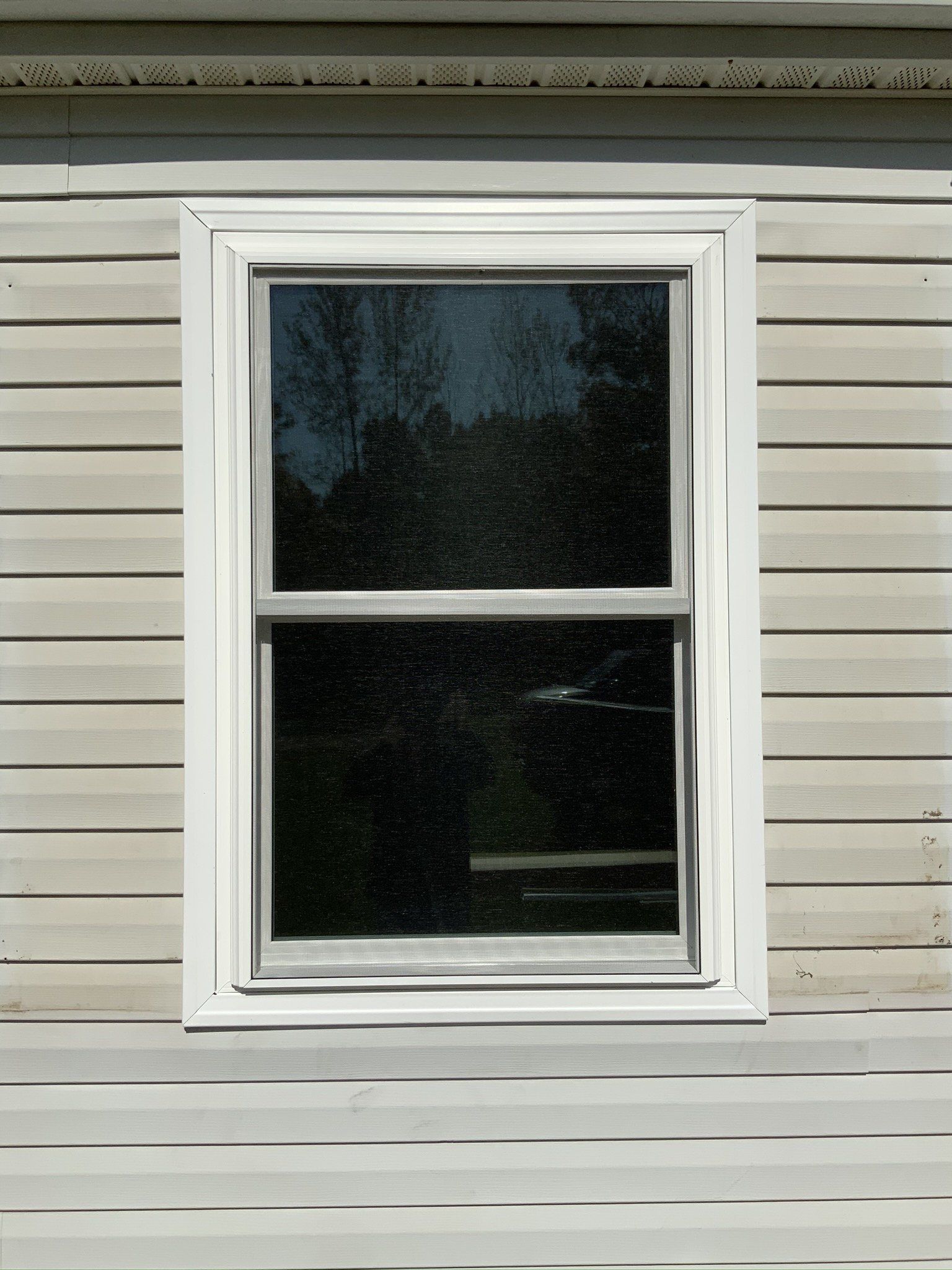 A window on the side of a house with a white frame
