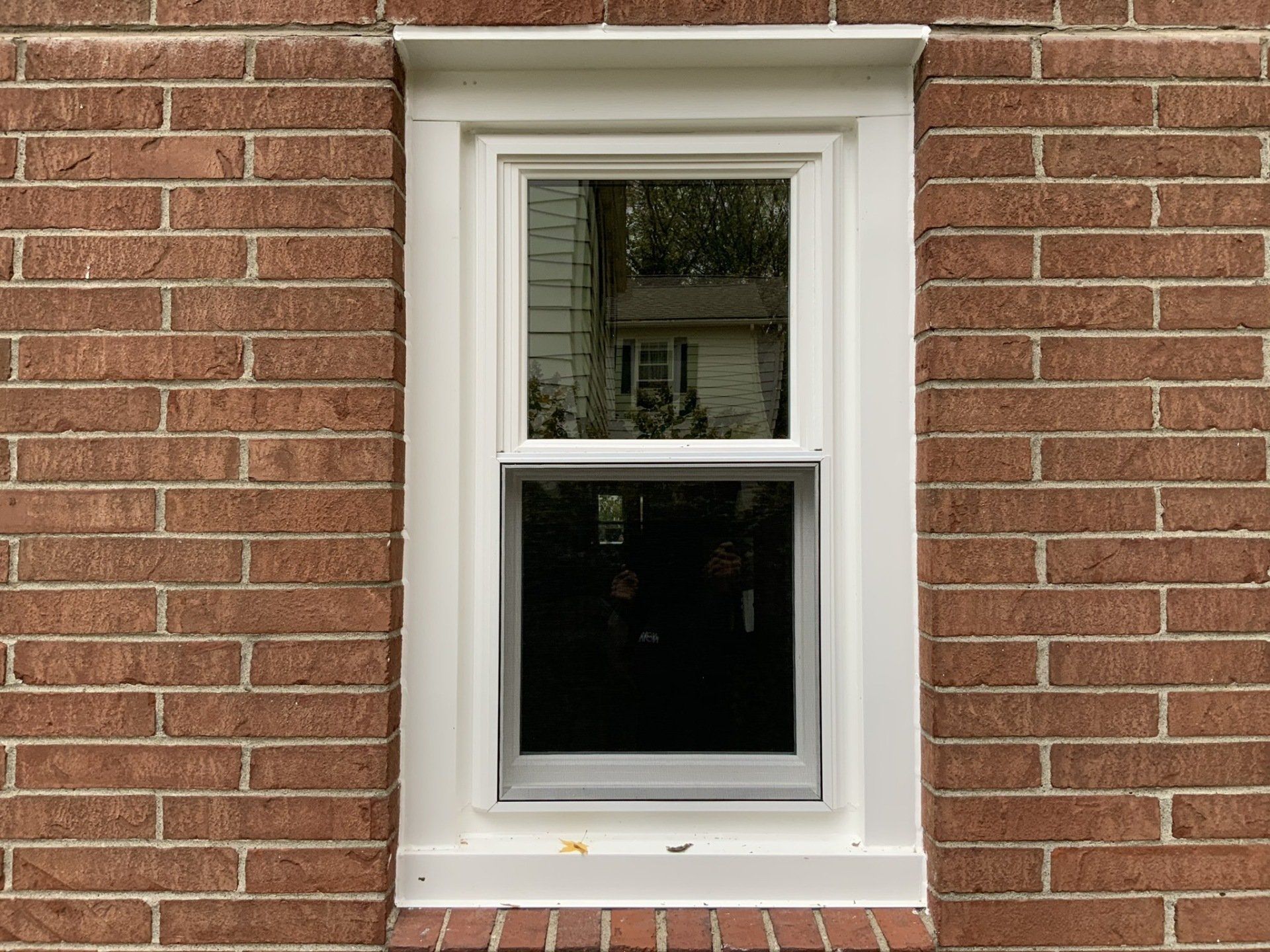 A white window is on a red brick wall.