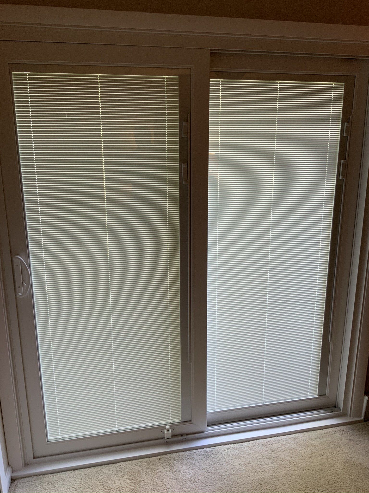 A sliding glass door with blinds on it in a room.