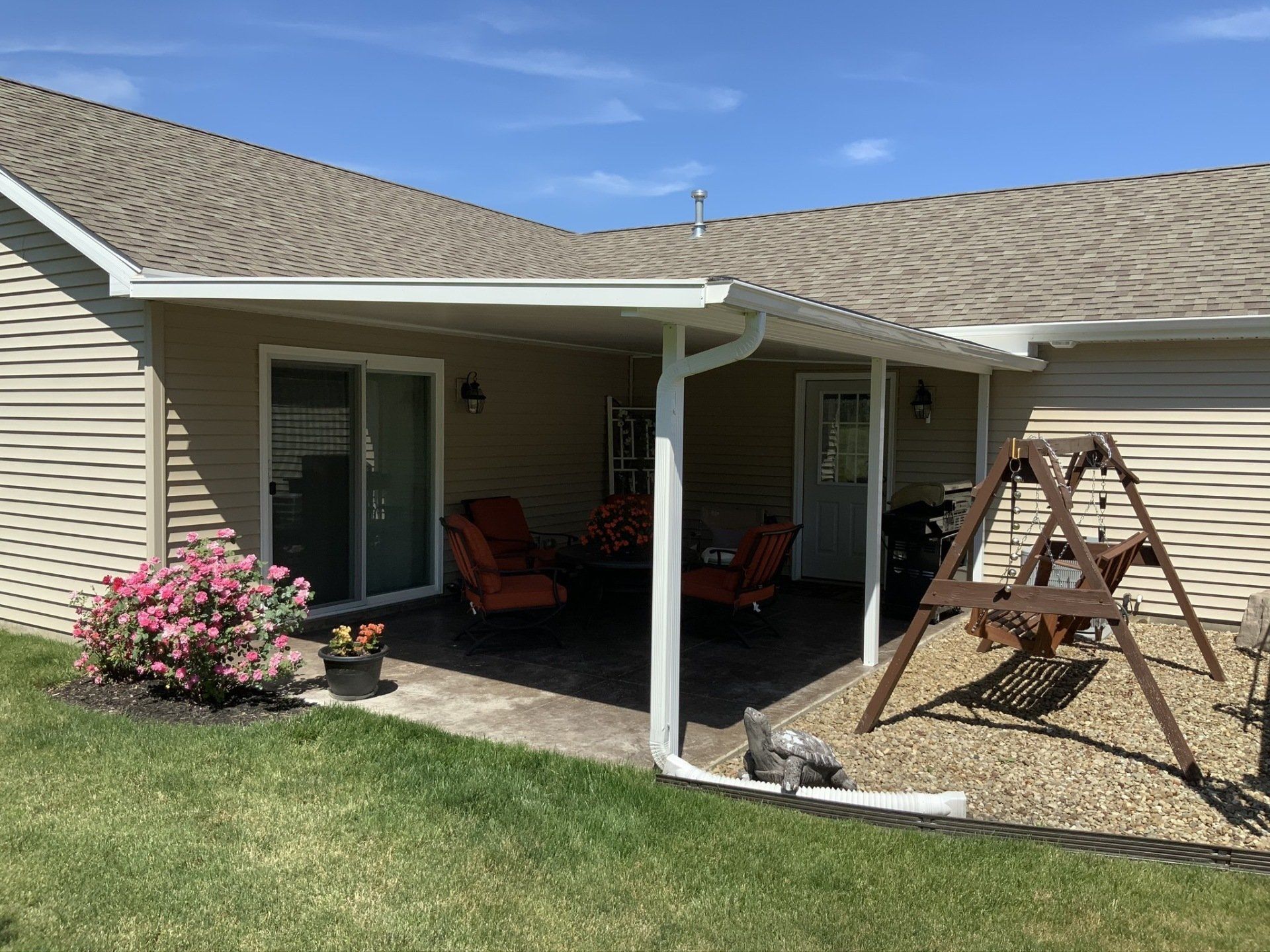 A house with a covered patio and a swing set in the backyard.