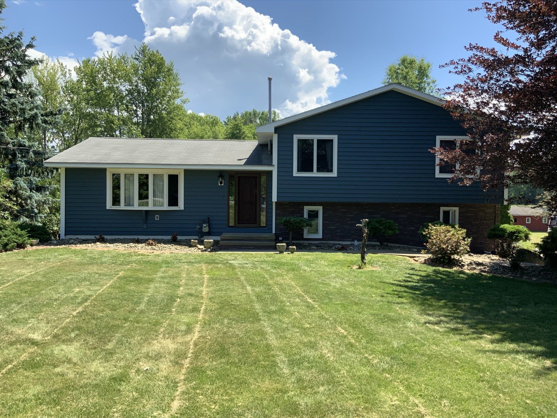 A blue house with a lush green lawn in front of it