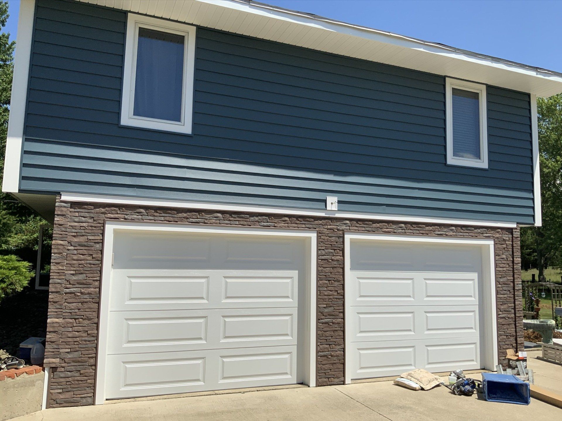 A house with a blue siding and white garage doors.