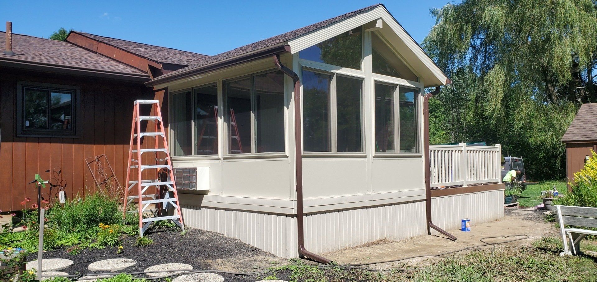 A screened in porch is being built in the backyard of a house.