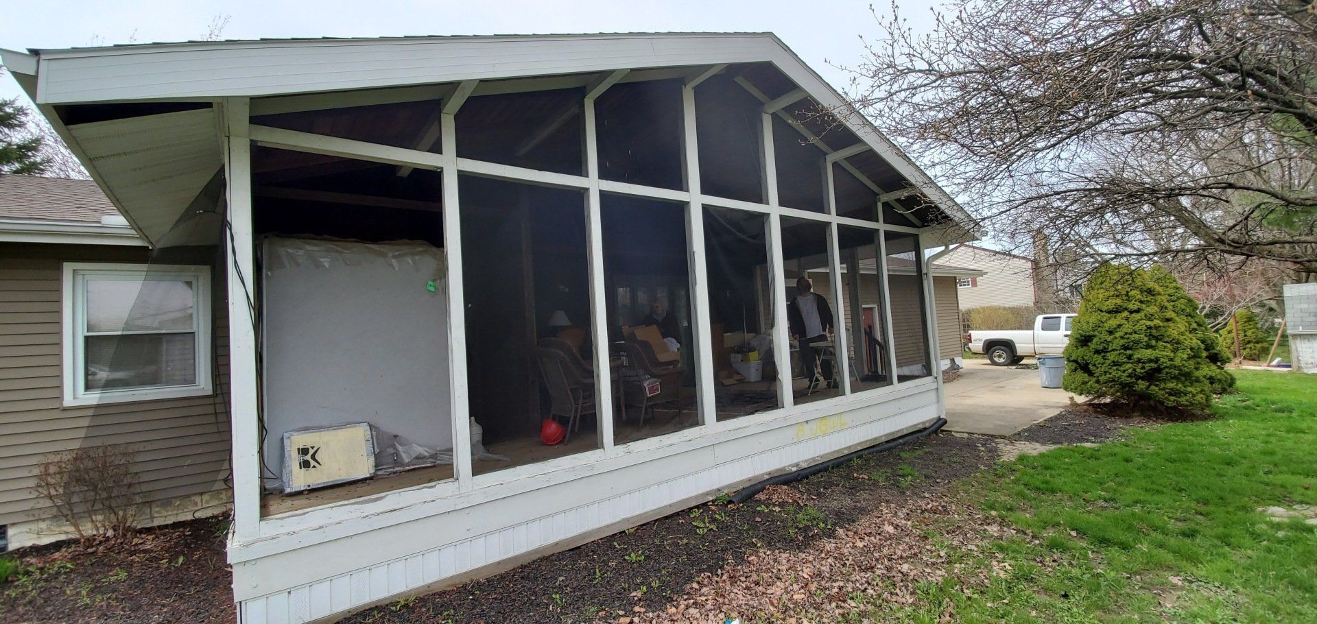 A house with a screened in porch and a truck parked in front of it.