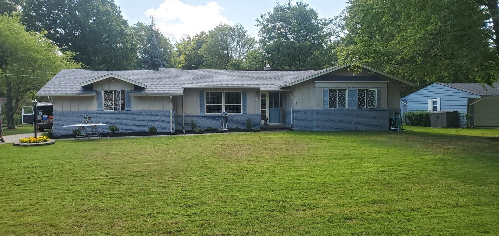 A blue and white house with a large lawn in front of it.