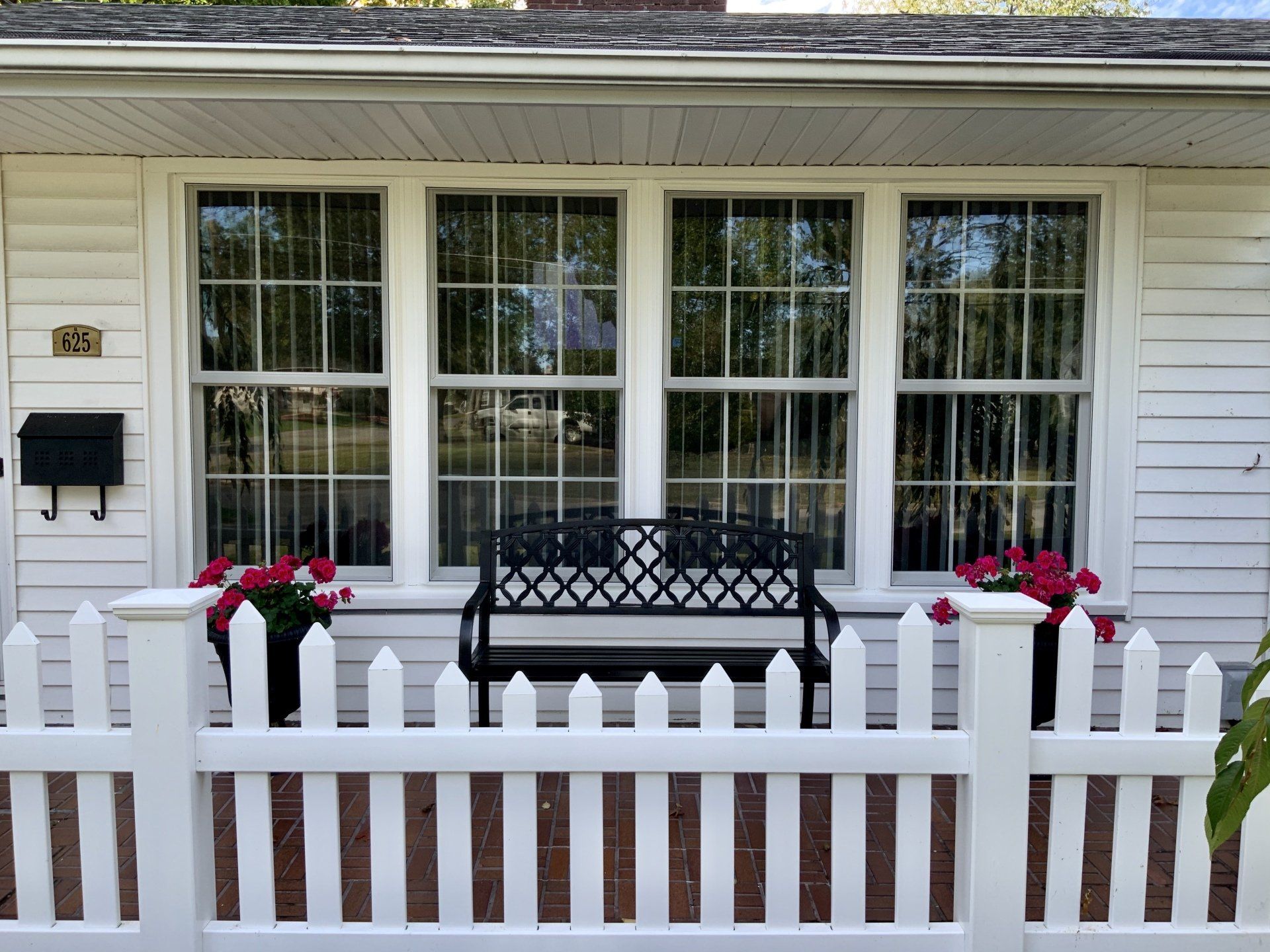 A white house with a white picket fence and a black bench
