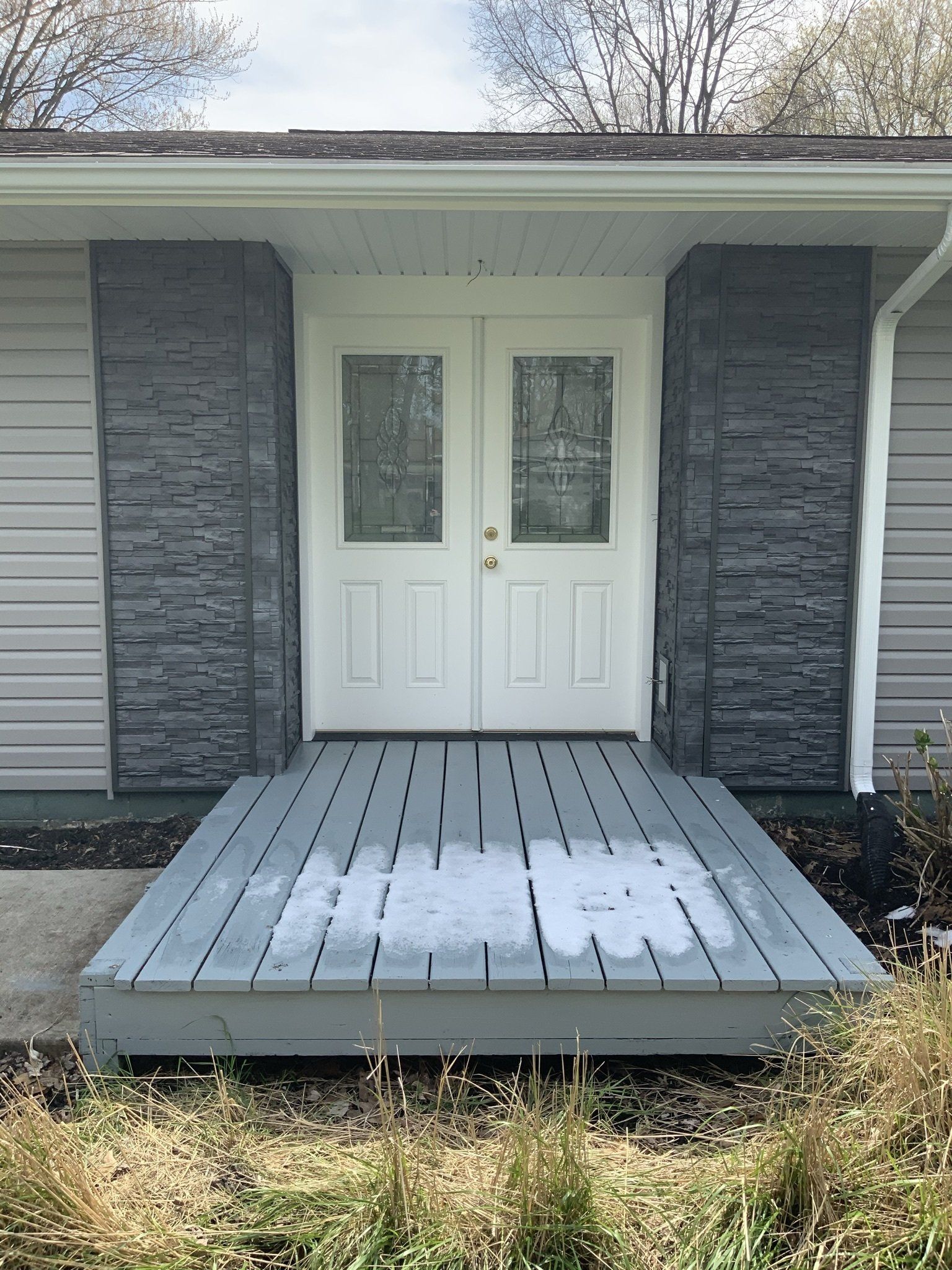 The front door of a house with a gray deck in front of it.