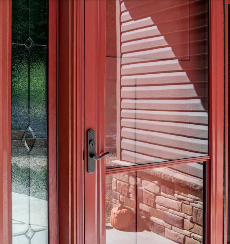 A red door with a reflection of a stone wall