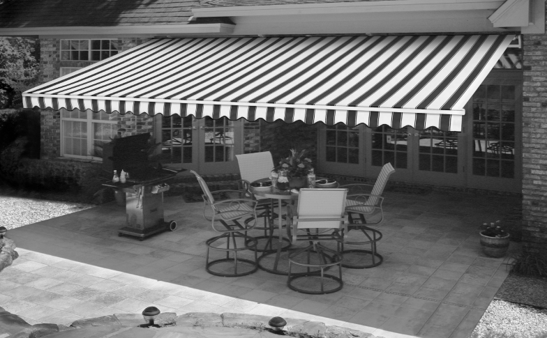 A black and white photo of a patio with a striped awning over it