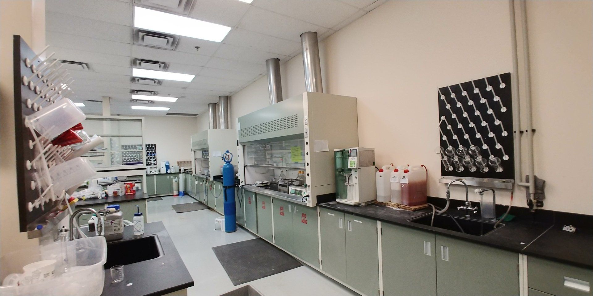 Un laboratoire avec de nombreuses armoires et une hotte.