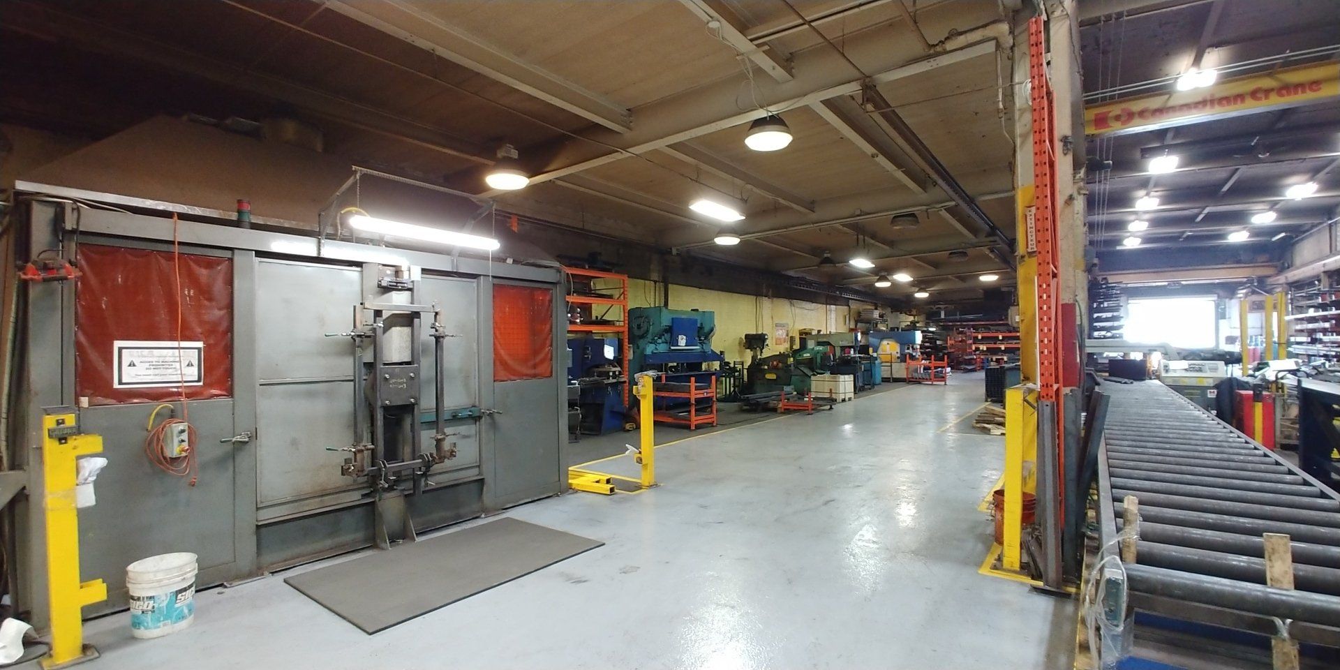 Un grand entrepôt rempli de nombreuses machines et d'un tapis roulant.