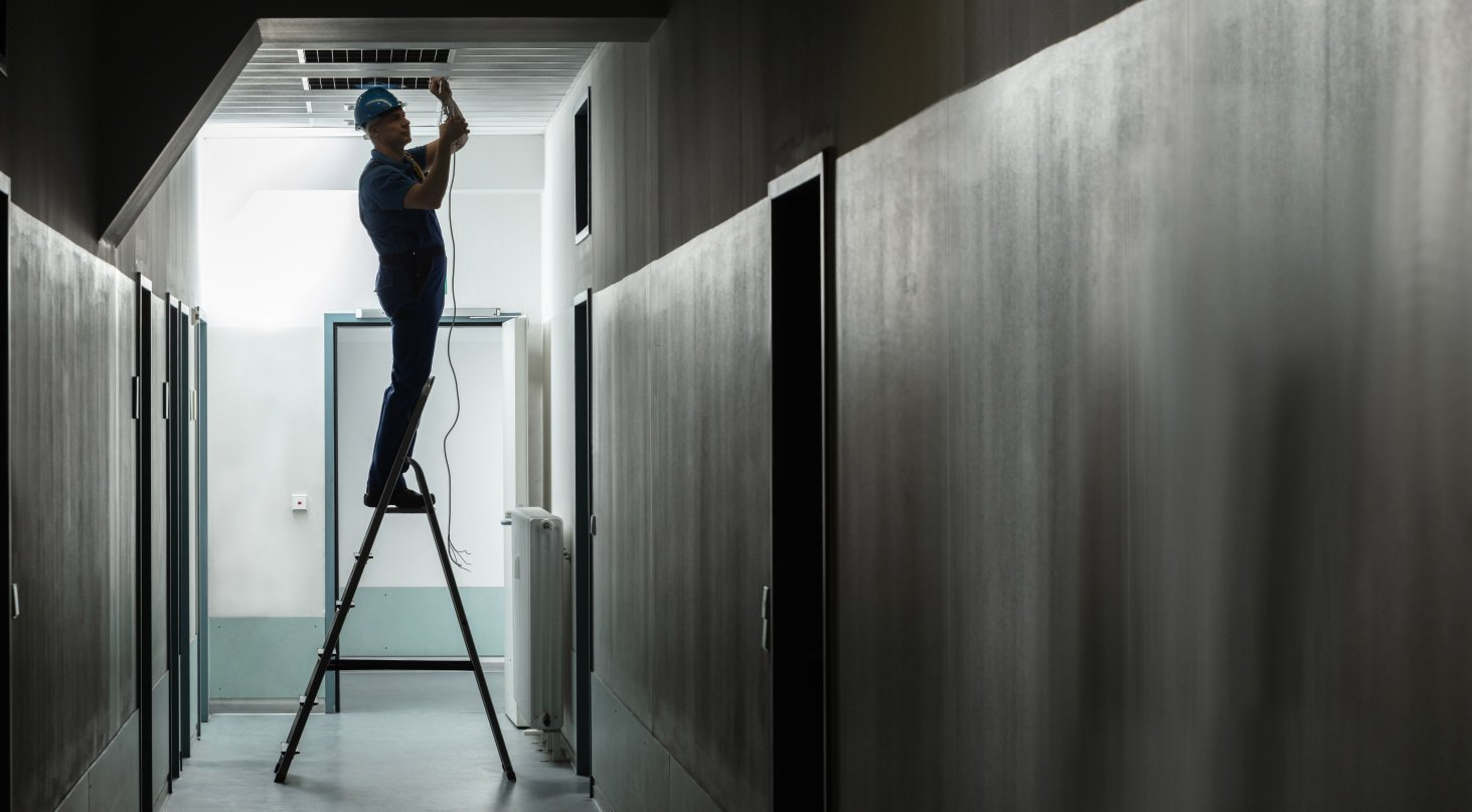 Un homme est debout sur une échelle dans un couloir.