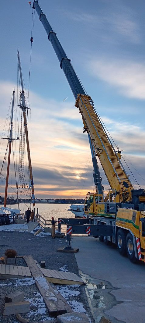 A large yellow crane is lifting a boat in the water.