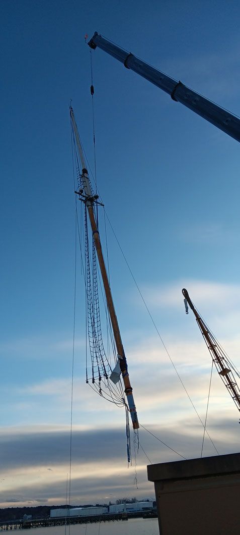 A crane is lifting a large object in the sky.