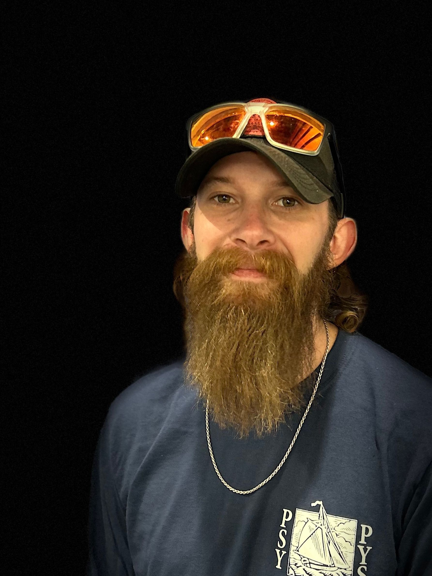 A man with a beard is wearing sunglasses and a hat.