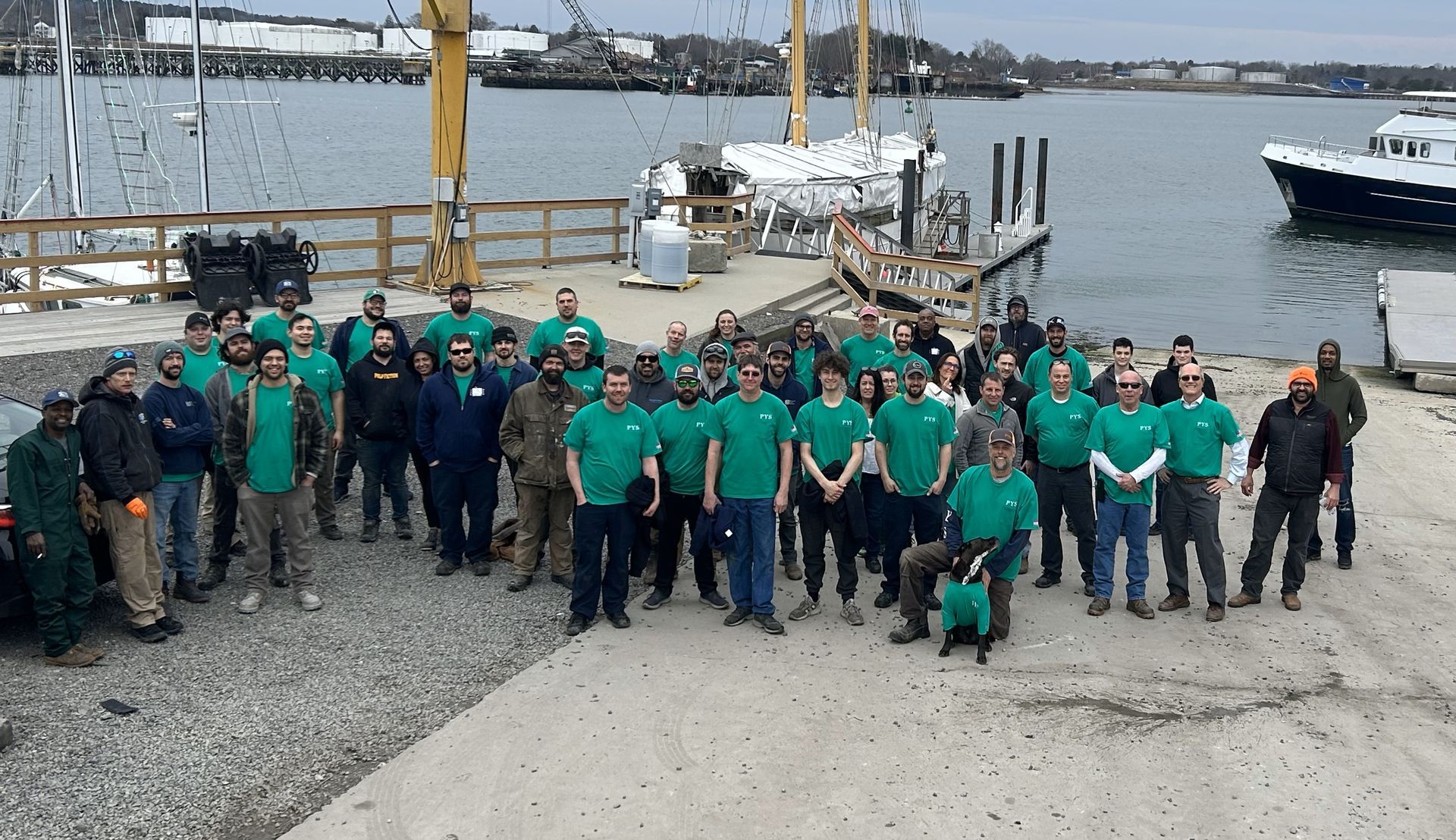 A large group of people are posing for a picture in front of a body of water.
