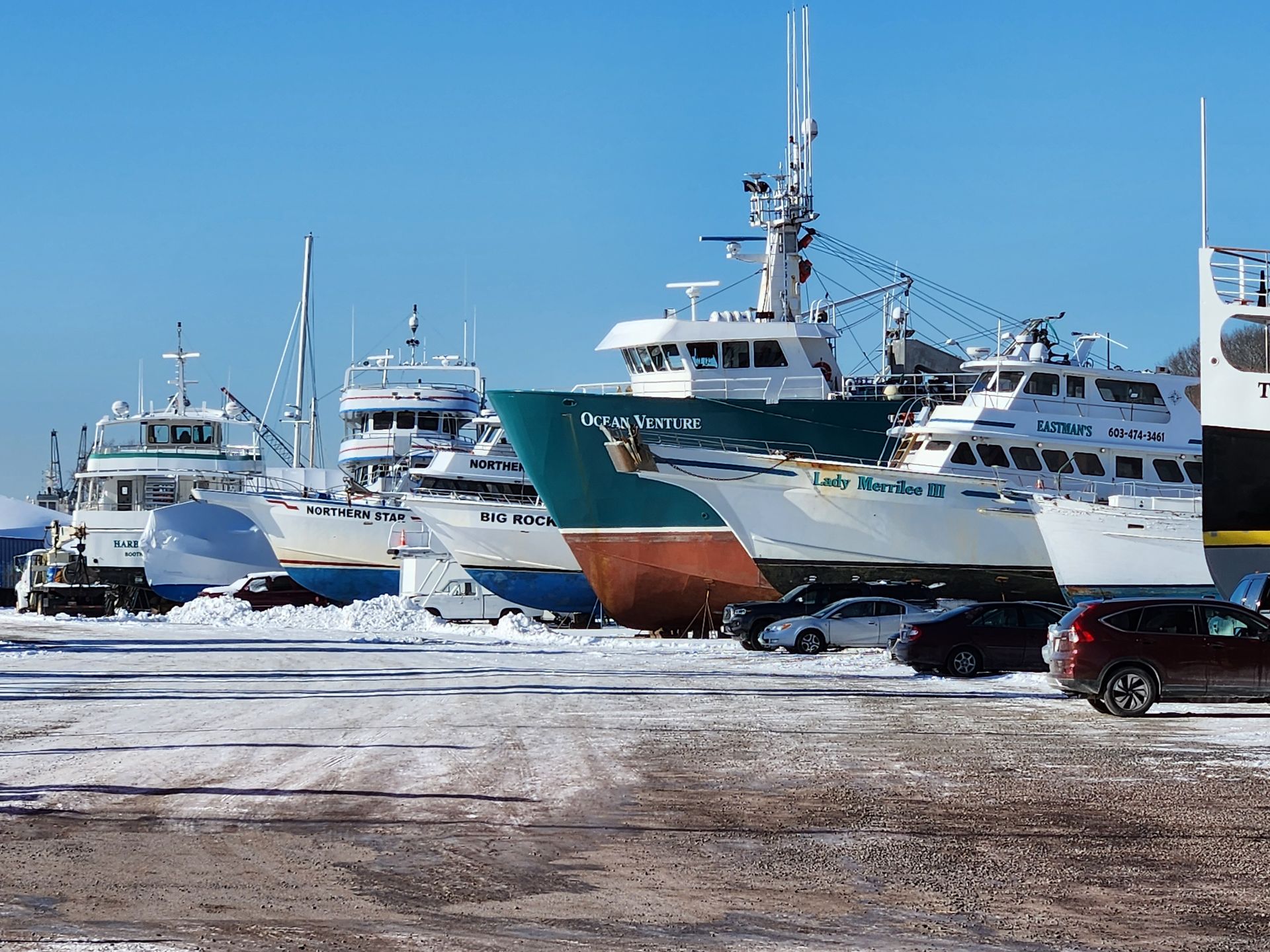 A row of boats are lined up in a snowy parking lot