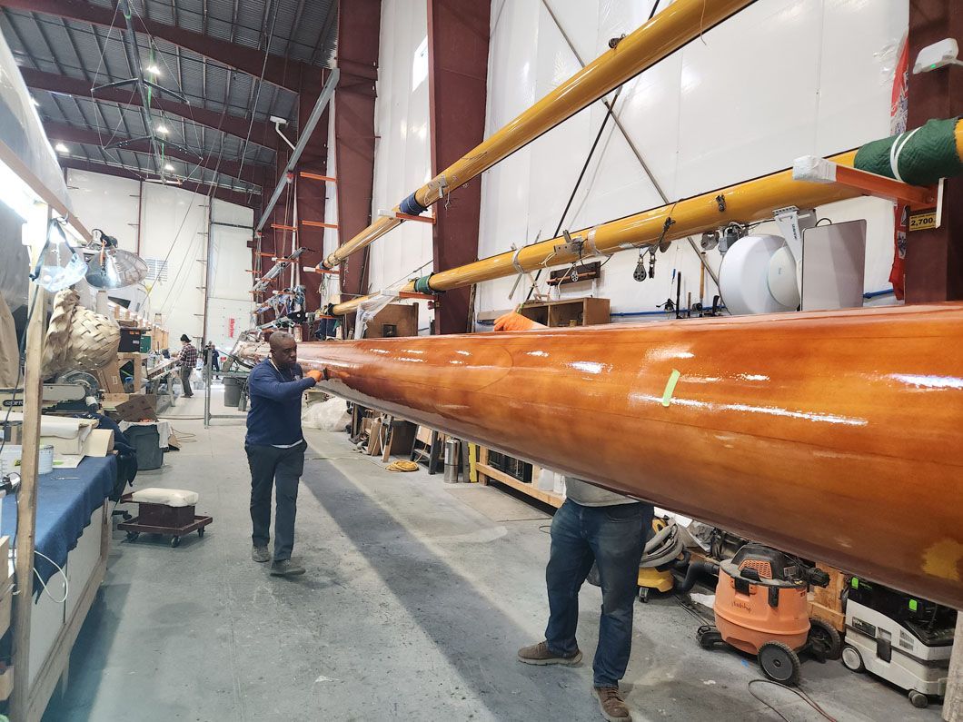 A man is carrying a large piece of wood in a warehouse.