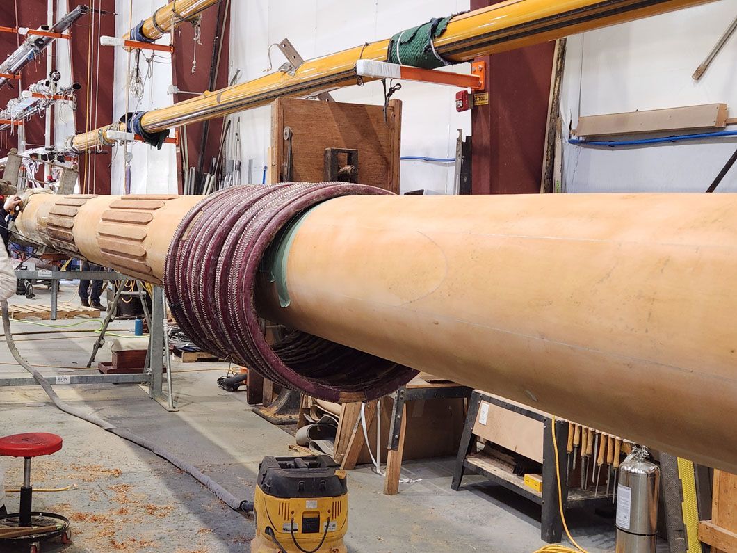 A large wooden pipe is being worked on in a factory.