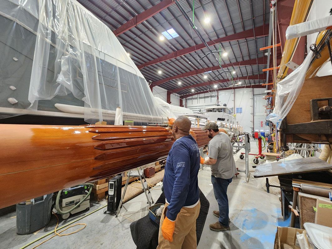 A group of men are standing in a warehouse looking at a boat.