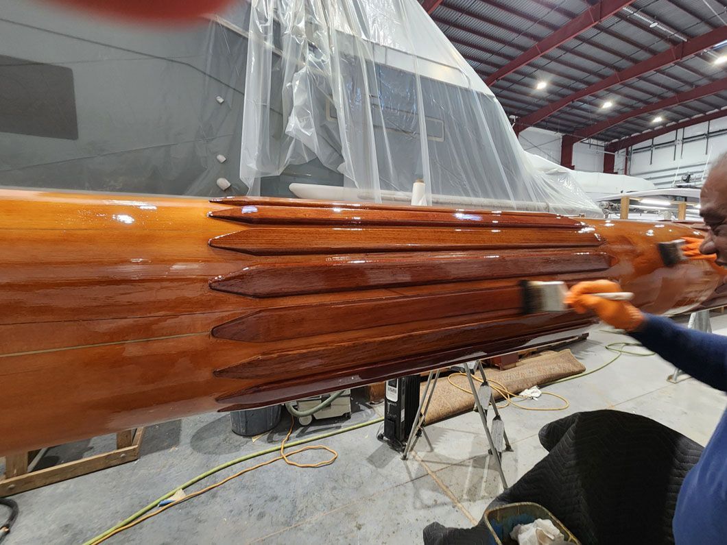A man is painting a wooden boat in a warehouse.